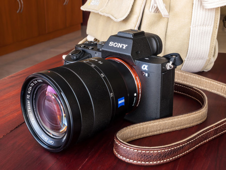 BANGKOK - FEBRUARY 19: Sony digital camera model A7II with normal Carl Zeiss zoom lens 24-70 mm f4 in natural light on red wooden table, was taken on February 19, 2015, in Bangkok Thailand.のeditorial素材