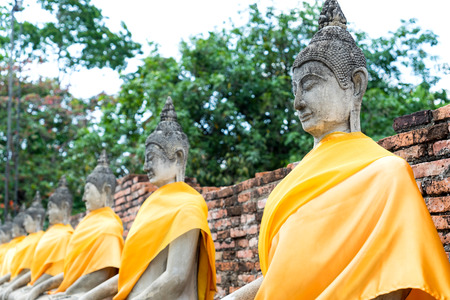 Old historic cement buddha statues along corridor of Thai temple in Ayuddhaya, Thailandの写真素材