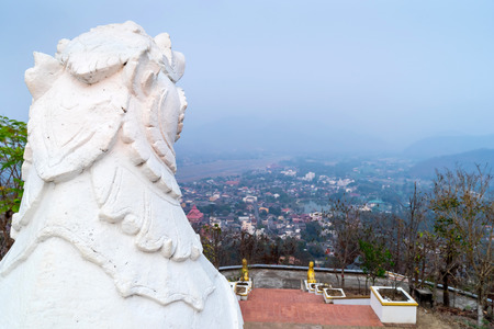 White Thai art lions at entrance of Wat Phra That Doi Gongmu with view of Maehongson city in evening periodの写真素材