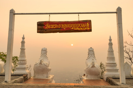 White Thai art lions at entrance of Wat Phra That Doi Gongmu with view of Maehongson city in evening periodのeditorial素材