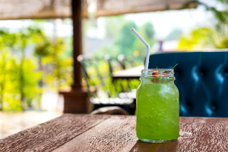 Green kiwi iced beverage in old fashion glass on wooden table in coffee shopの写真素材
