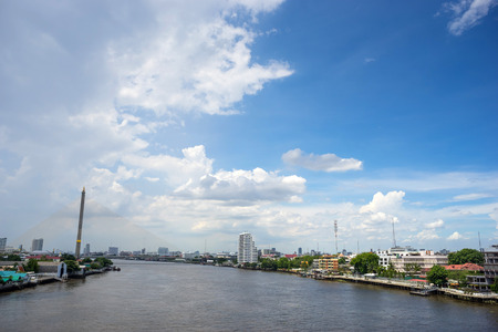 Chaophraya river and Rama VIII bridge view with surrounded buildings and resident area under cloudy blue sky in Bangkok Thailandのeditorial素材