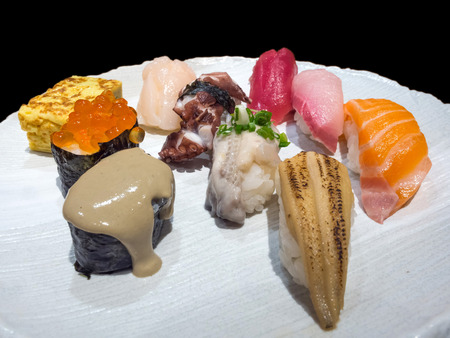Sushi is authentic luxury delicious Japanese food, made from rice and raw fish, decorated on white dish isolated on black backgroundの写真素材