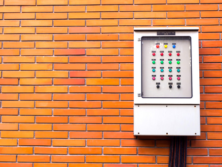 Orange brick wall with electricity control metal boxの写真素材