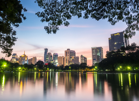 BANGKOK - DECEMBER 18: Skyscraper building cityscape with reflection on lake in park in Bangkok, Thailand, in evening twilight sky, was taken on December 18, 2015.のeditorial素材