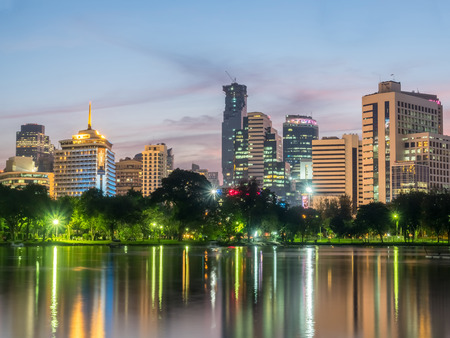 BANGKOK - DECEMBER 18: Skyscraper building cityscape with reflection on lake in park in Bangkok, Thailand, in evening twilight sky, was taken on December 18, 2015.のeditorial素材