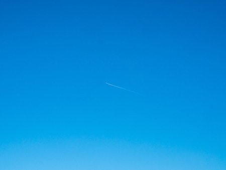 Cloud and jet contrail with blue sky backgroundの写真素材