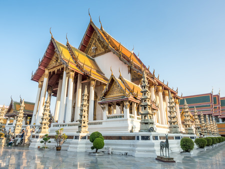 Delicate Thai art and large main church of Wat Suthat in Bangkok, Thailand, under blue sky in eveningの写真素材