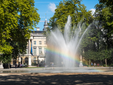 Artificial fountain with reflected bubble water rainbow in natural park under clear blue skyの写真素材
