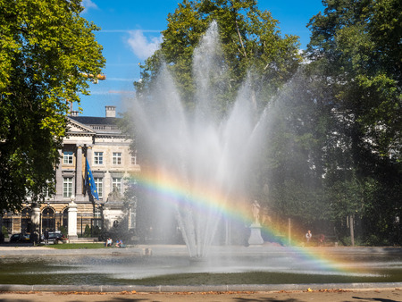 Artificial fountain with reflected bubble water rainbow in natural park under clear blue skyの写真素材