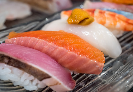Sushi is luxury authentic Japanese food, made by various raw fish place on sour rice, selective focus on one pieceの写真素材