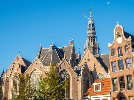 Top of the Old Church (Oude Kerk) in main red light district in Amsterdam, Netherlands, under blue skyの写真素材