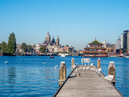 AMSTERDAM - OCTOBER 2: Saint Nicholas church with surrounding buildings and sea gull under blue sky in Amsterdam, Netherlands, on October 2, 2015.のeditorial素材