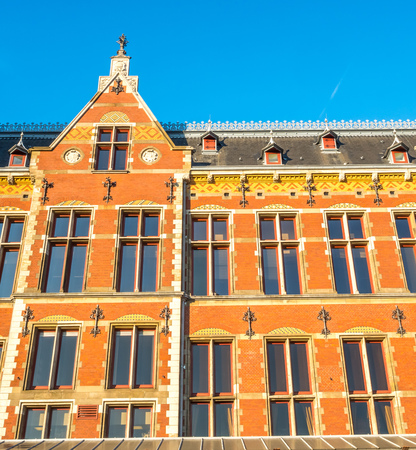 Amsterdam train station building is outstanding with unique architecture design under afternoon sunlight under cloudy blue skyの写真素材