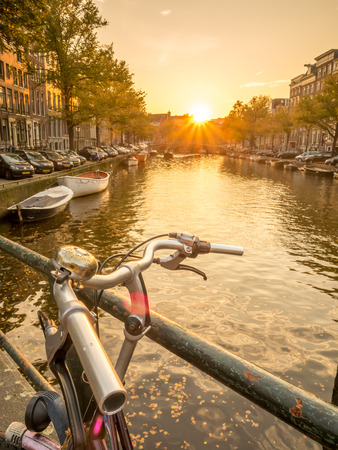 AMSTERDAM - OCTOBER 3: Twilight evening city scene of Amsterdam with bicycle and transportation along canal in Netherlands, on October 3, 2015.のeditorial素材