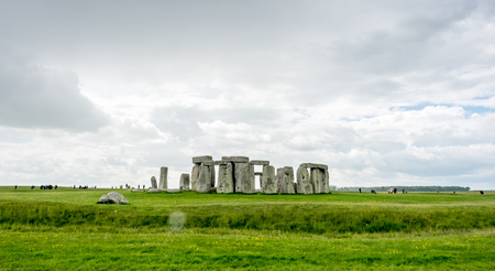 Stonehenge an ancient prehistoric stone monument near Salisbury, Wiltshire, England, with unrecognized tourist nearby.の写真素材