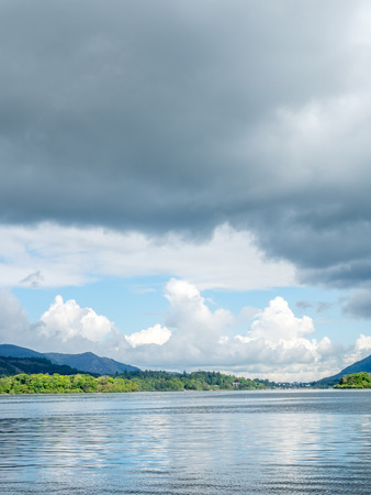 Lake side coast view with mountain background under cloudy evening twilight skyの写真素材