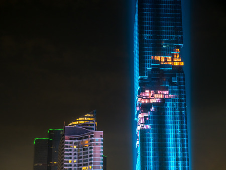 BANGKOK - AUGUST 28: Mahanakorn skyscraper building, the tallest building in Thailand, in grand opening rehearsal light show under twilight evening sky in Bangkok, Thailand, on August 28, 2016.のeditorial素材