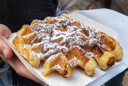Waffle with topped white sugar on paper dish on handの写真素材
