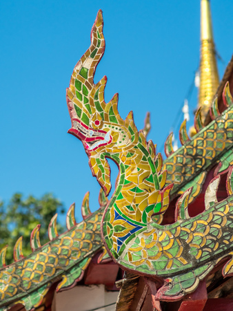 Wat Phra That Doi Kham main church and delicate Thai art on roof under clear blue sky in Chiangmai, Thailandの写真素材