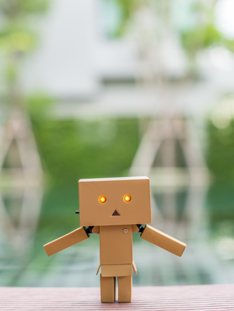 Extend the arms action of cute box doll standing at outdoor park with natural light, selective focus at its eyeの写真素材