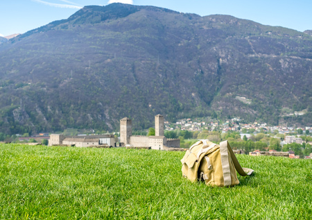 Camera bag on outdoor green grass with Castelgrande and Bellinzona cityscape view in backgroundのeditorial素材