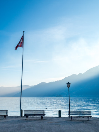 Outdoor scene view side of Lake Maggiore with bench and flag in Locarno, Switzerlandの写真素材