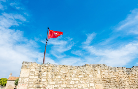 LES BAUX-DE-PROVENCE - APRIL 12 : Flag sign on stone wall of Castle of Les Baux-de-provence, France, under cloudy blue sky, on April 12, 2017.の写真素材