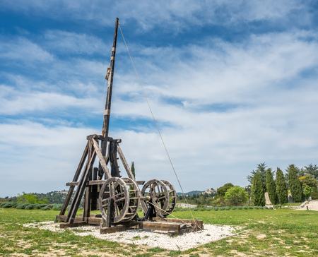 Catapult, on of the seige engines in Castle of Les Baux-de-provence, France, with grass field under cloudy blue skyの写真素材