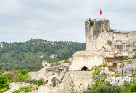 Lower courtyards of area around Chateau des Baux-de-provence in france with unrecognized tourists, under cloudy blue skyの写真素材