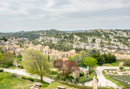 Lower courtyards of area around Chateau des Baux-de-provence in france with unrecognized tourists, under cloudy blue skyの写真素材