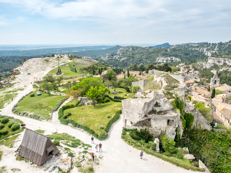 Lower courtyards of area around Chateau des Baux-de-provence in france with unrecognized tourists, under cloudy blue skyの写真素材