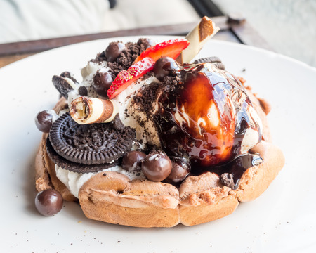 Sweety dessert, strawberry, chocolate, waffle, whipping cream and cookie on white dish, selective focus at one pointの写真素材