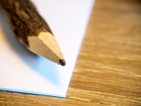Wooden carbon pencil on white paper, on wooden table, selective focus at pencil tipの写真素材
