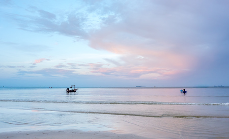 Little fisherman boat near sand beach under cloudy blue sky in Thailandの写真素材
