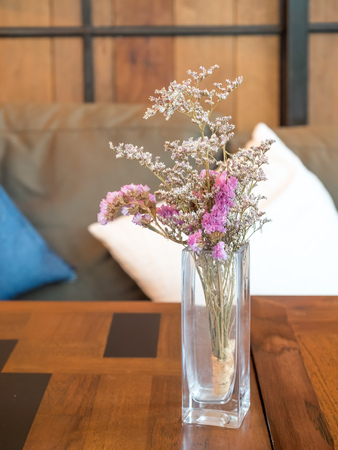 Little purple flowers in glass vase, on wooden table, in restaurantの写真素材