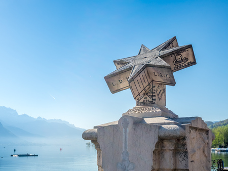 ANNECY, FRANCE - APRIL 14 : Outdoor sundial in park nearby lake with mountains view background in Annecy, France, on April 14, 2017.のeditorial素材