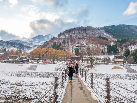 GIFU, JAPAN - NOVEMBER 25 : Tourists cross bridge over river, entrance of Shirakawa village the UNESCO World Heritage, in early winter season with snow, in Gifu, Japan, on November 25, 2017.のeditorial素材