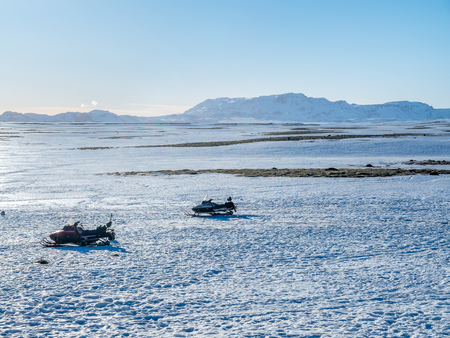 Snow field with ski mobile and mountains under clear blue sky in rural area of Icelandの写真素材
