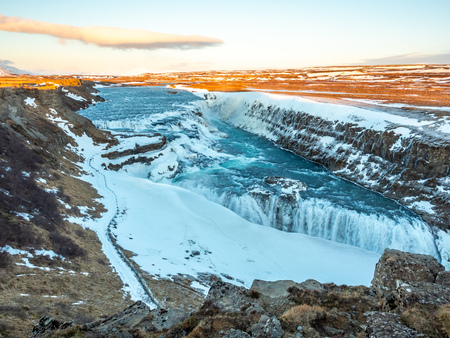 Gullfoss, one of the strongest waterfall in Iceland, with snow and ice in winter season, under vanilla evening twilight sky in Icelandの写真素材