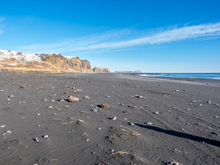 Reynisfjara black sand beach is landmark of Vik town in Iceland, surrounded with basalt mountains, under blue sky in winter seasonの写真素材