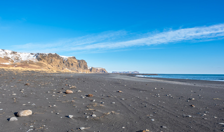 Reynisfjara black sand beach is landmark of Vik town in Iceland, surrounded with basalt mountains, under blue sky in winter seasonの写真素材