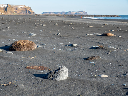 Reynisfjara black sand beach is landmark of Vik town in Iceland, surrounded with basalt mountains, under blue sky in winter seasonの写真素材