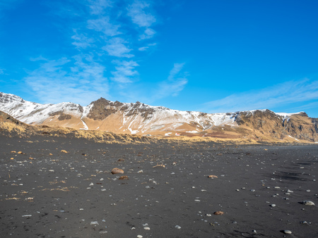Reynisfjara black sand beach is landmark of Vik town in Iceland, surrounded with basalt mountains, under blue sky in winter seasonの写真素材