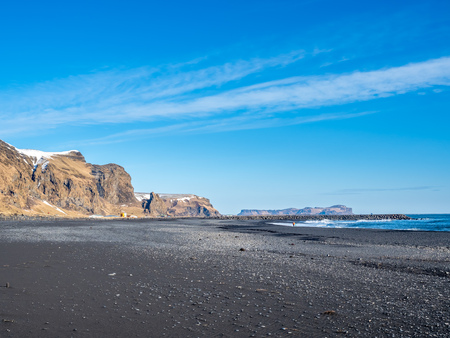 Reynisfjara black sand beach is landmark of Vik town in Iceland, surrounded with basalt mountains, under blue sky in winter seasonの写真素材