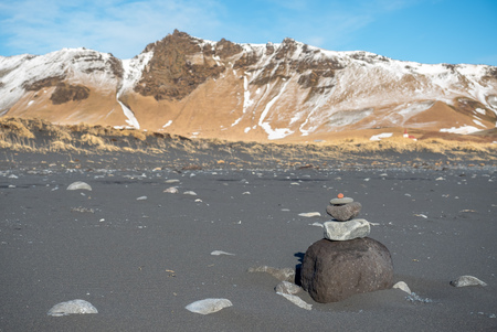 Reynisfjara black sand beach is landmark of Vik town in Iceland, fine black sand with small stones on beach with snow moutains in backgroundの写真素材