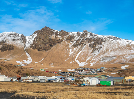 House in village near black sand beach in Vik town in Iceland with snow mountains in background under clear blue sky in winter seasonのeditorial素材