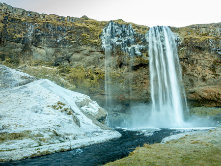 Siljalandsfoss waterfall, one of landmark in Iceland, large waterfall with natural cliff in winter season with snow and ice aroundの写真素材