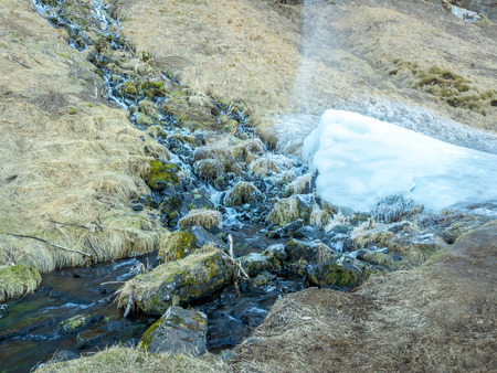 Large waterfall near Seljalandsfoss waterfall with large snow with small ascending fountain, in winter season in Icelandの写真素材