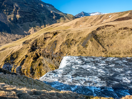 Streaming river at top of Skogafoss waterfall with snow and ice in winter season in Icelandの写真素材